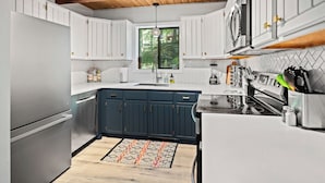 A modern kitchen with white cabinets, a black countertop, and a wooden ceiling. - Eclectic Family Poconos Escape! Skiing 5min away! Firepit, Near Woodloch/winery! (Lackawaxen)