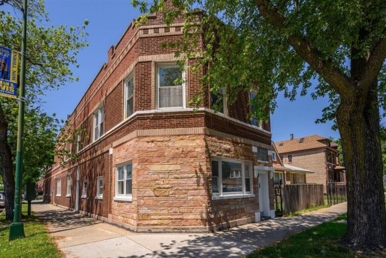 A corner brick building with a stone facade, large windows, and a visible door.