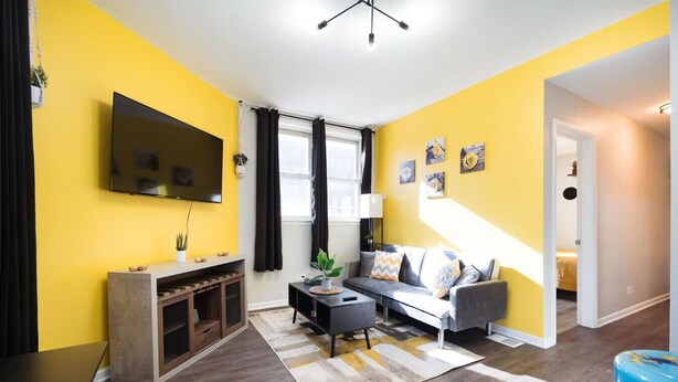 Ein Wohnzimmer mit einem Flachbildfernseher, einem Sofa, einem Couchtisch und einer Treppe, die in einen anderen Raum führt.