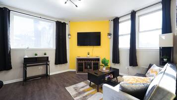A living room with a sofa, a coffee table, a TV, and a plant.