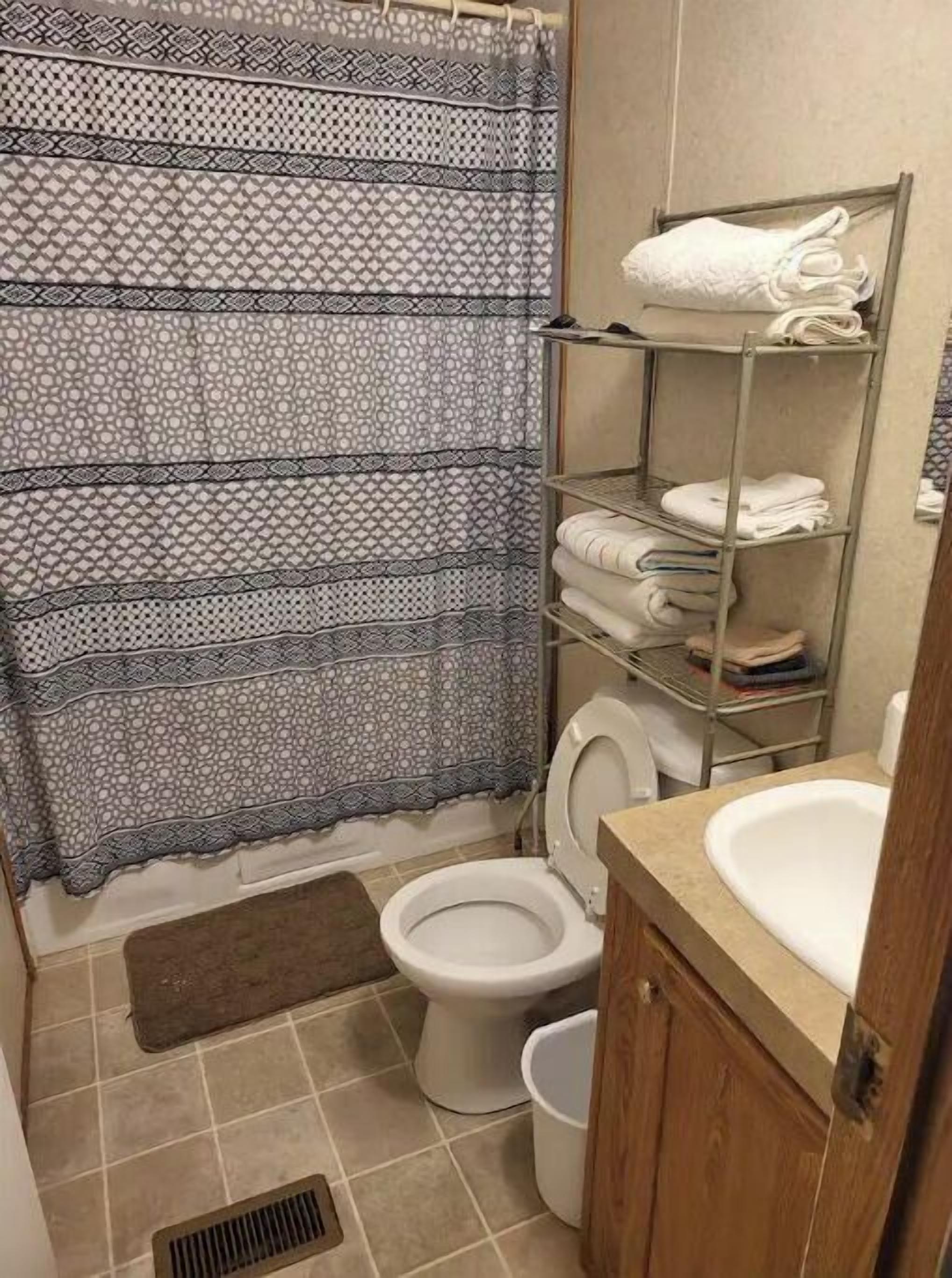 A small bathroom with a toilet, a sink, a shower curtain, and a towel rack.