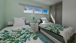 Un dormitorio con dos camas, una ventana y una mesita de noche.