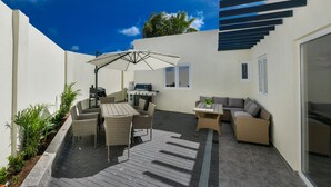 Un patio al aire libre con comedor, una parrilla y una zona de estar con sofá y sillones.