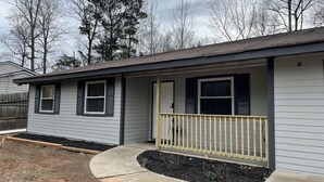 A single-story house with a front porch, a small deck, and a fenced yard.