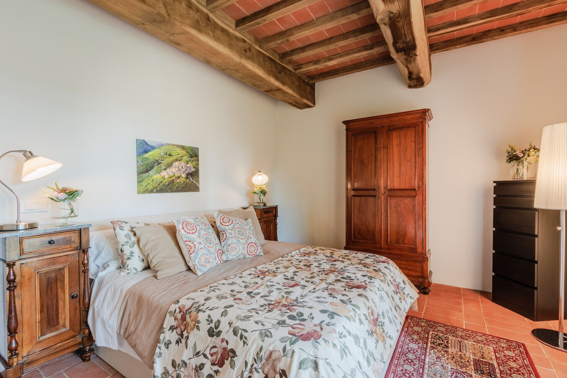 A bedroom with a wooden bed, a nightstand, a dresser, and a large wardrobe.
