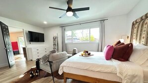 A bedroom with a bed, a ceiling fan, a TV, and a window with curtains. - The Hugging Cactus. Old Town's Finest.  (Scottsdale)