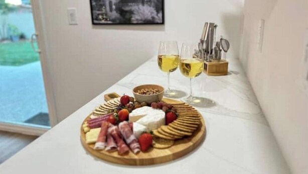 A room with a marble countertop displaying a charcuterie board, two glasses of white wine, and a bowl of nuts. - The Hugging Cactus. Old Town's Finest.  (Scottsdale)