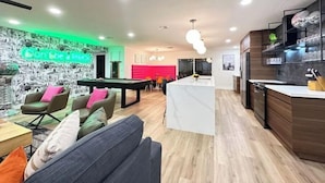 A modern living room with a pool table, a sofa, and a bright neon sign. - The Hugging Cactus. Old Town's Finest.  (Scottsdale)