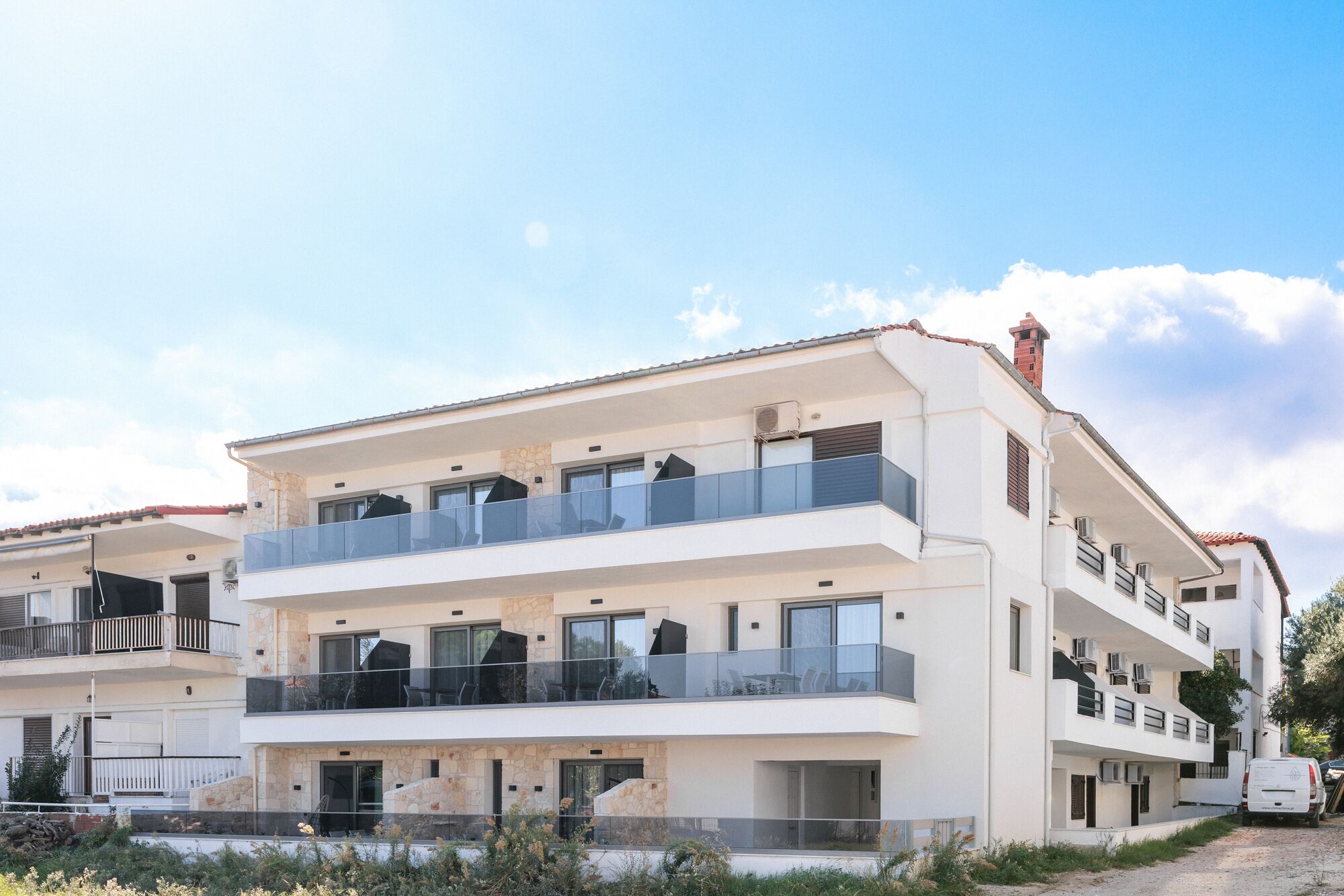 Un immeuble résidentiel moderne à plusieurs étages, doté de balcons, d’une façade en pierre et surplombant un ciel dégagé.