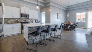 Une cuisine moderne avec des meubles blancs, un plan de travail en granit et des tabourets de bar noirs.