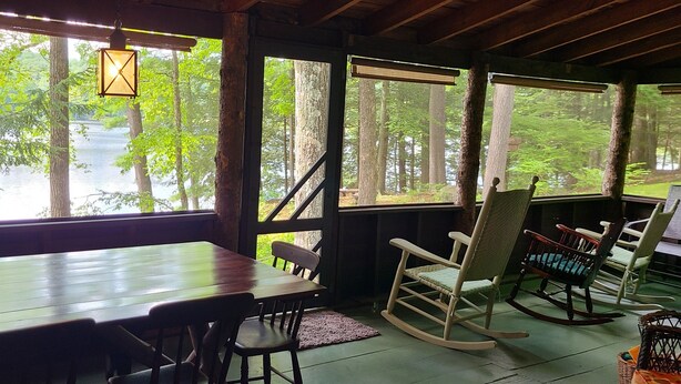 Eine Holzterrasse mit Tisch und Stühlen mit Blick auf eine bewaldete Gegend.