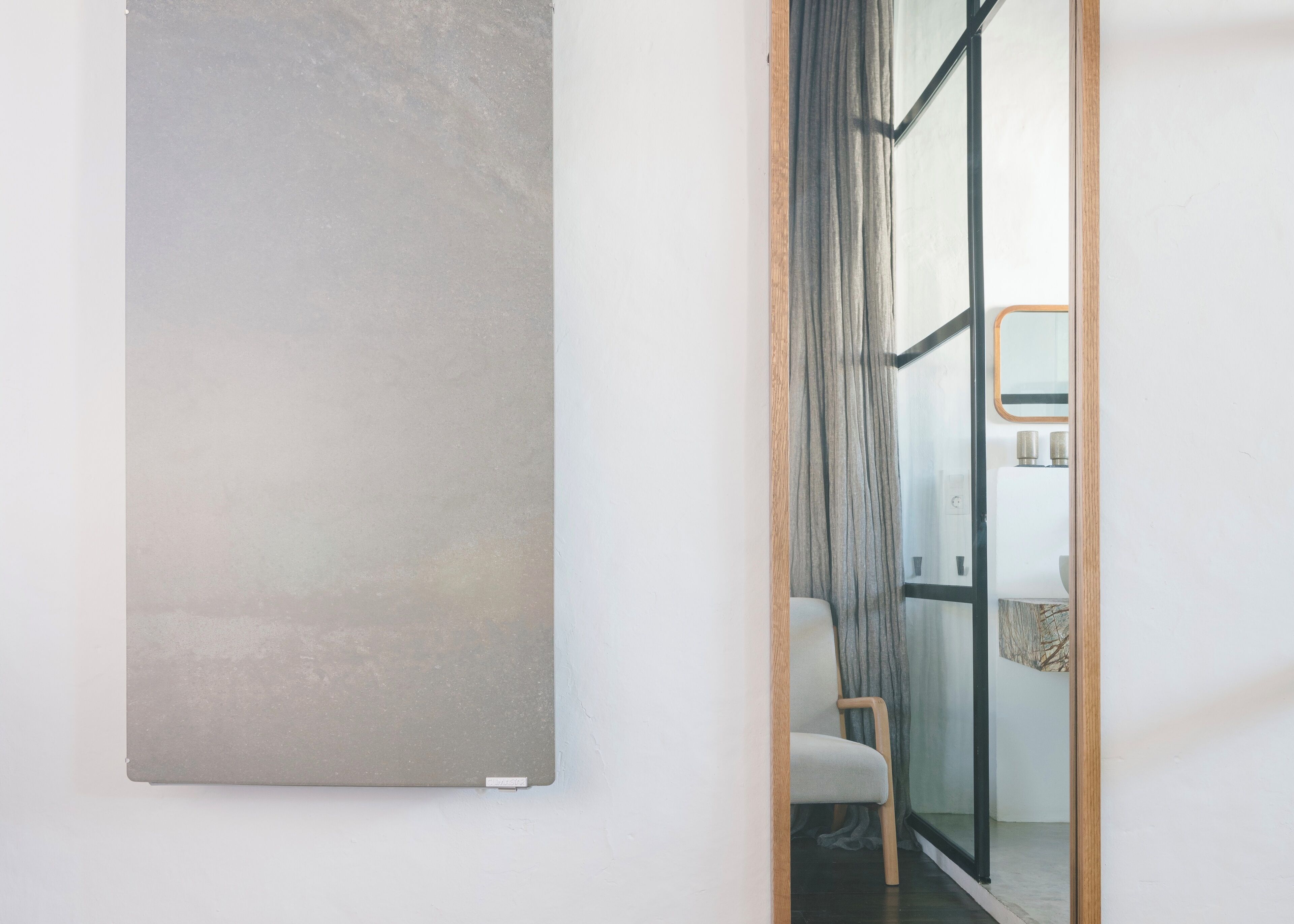Un baño moderno con cabina de ducha de vidrio, una silla blanca y un cuadro abstracto grande en la pared.