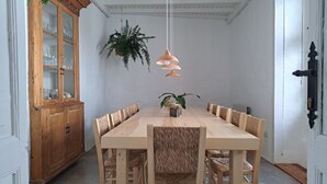 A dining area with a wooden table and chairs, a cabinet with glass doors, and hanging plants. - Casa de las Flores - Hotel Boutique Lanzarote (Teguise)