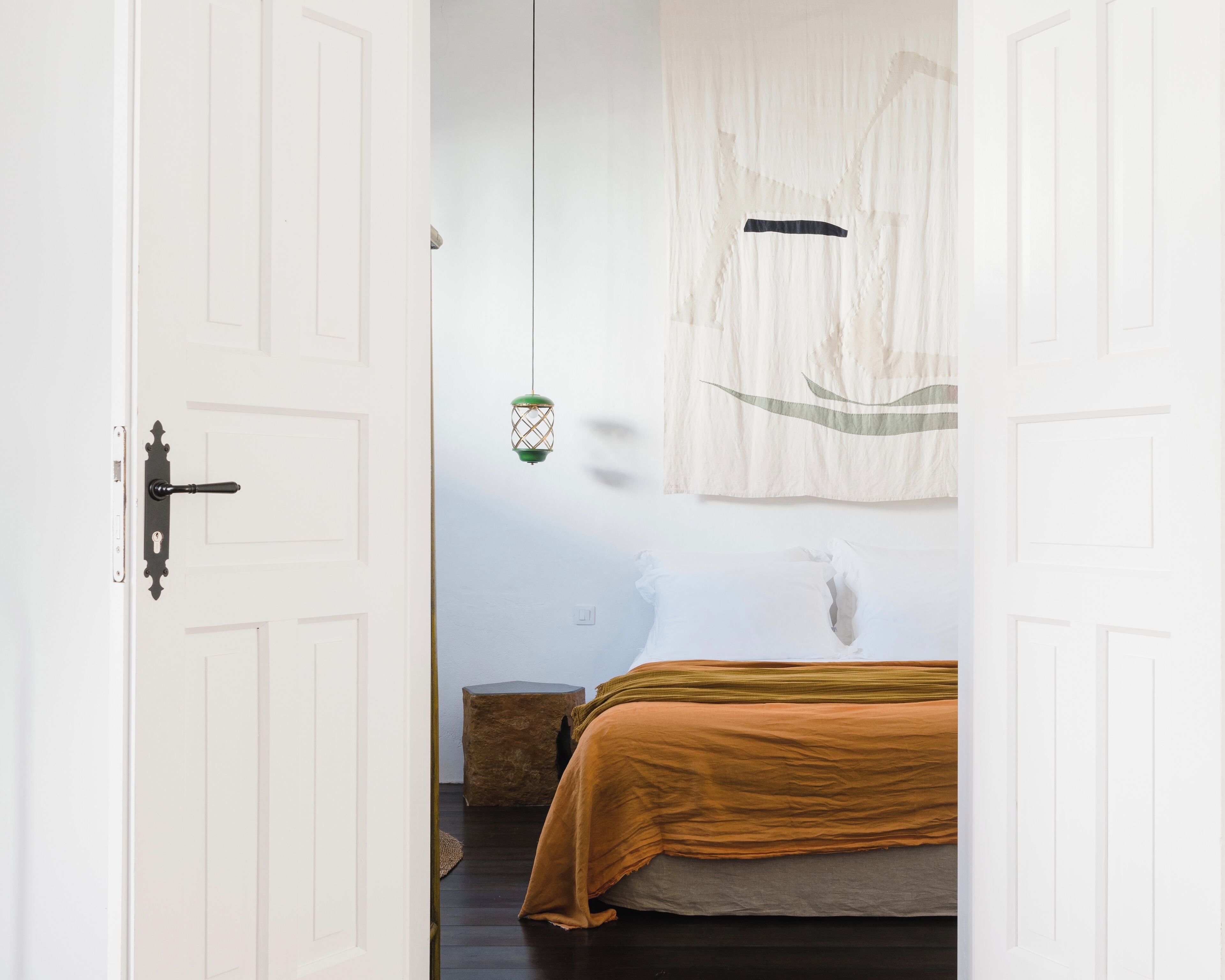 Een slaapkamer met een bed, een hanglamp en een muur met een eenvoudig ontwerp.