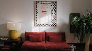 A living room with a red sofa, a yellow lamp, a framed artwork, and a potted plant.