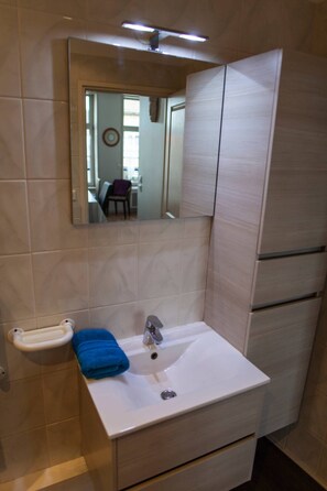 Un baño con un lavabo blanco, un espejo y una toalla.