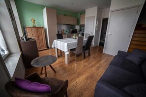 Un espacio habitable compacto con comedor, kitchenette y una escalera que sube a otro nivel.