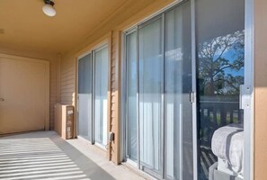A covered porch with a sliding glass door, a small table, and a chair.