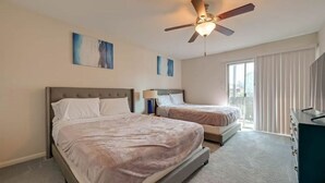 A hotel room with two beds, a ceiling fan, and artwork on the walls.