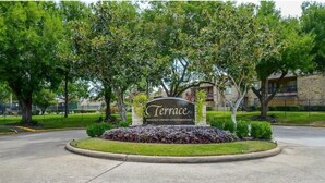 A sign for 'Terrace' private owned condominiums with a landscaped area and trees.