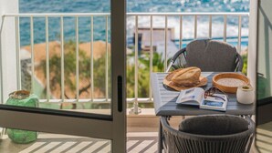 A balcony with a view of the ocean, a table with a book, a bowl, and a candle. - Premium quiet apt, Funchal seafront | Oceanbreeze (Funchal)