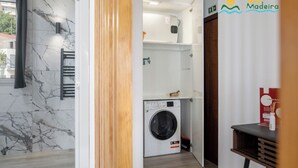 A compact laundry room with a washing machine, a towel rack, and a small cabinet. - Premium quiet apt, Funchal seafront | Oceanbreeze (Funchal)