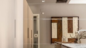 Una cocina moderna con una isla central, iluminación empotrada y una obra de arte de gran tamaño con marco de madera en la pared.
