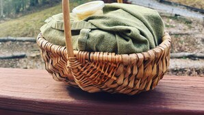 Un panier en osier doté d’une anse, posé sur une surface en bois.