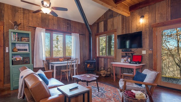 Un intérieur de chalet chaleureux avec une cheminée, des murs en bois, un téléviseur et un coin repas.
