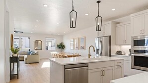 A modern kitchen with white cabinets, stainless steel appliances, and a central island. - Somewhere on a Beach: Desert Color Lagoon + Beaches (St. George)