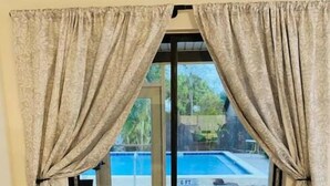 A room with a sliding glass door leading to a pool area. - Lovely 1 bedroom unit with pool (Sebring)