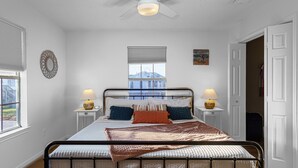 Een slaapkamer met een bed, bedlampen, een raam met uitzicht en een deur.