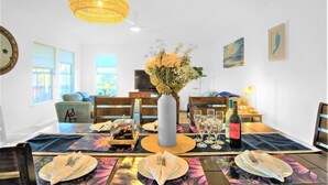 Een eethoek met een tafel voor vier personen, een vaas met bloemen en een fles wijn.