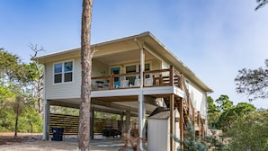 A two-story house with a covered porch and a fenced deck. - FREE POOL HEAT thru 2026! Golf Cart, Private Pool, Dogs OK (St. George Island)