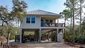 A two-story house with a covered porch and a balcony. - FREE POOL HEAT thru 2026! Golf Cart, Private Pool, Dogs OK (St. George Island)