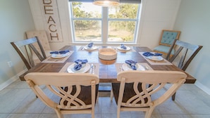A dining room with a wooden table set for four, surrounded by wooden chairs. - FREE POOL HEAT thru 2026! Golf Cart, Private Pool, Dogs OK (St. George Island)