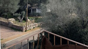 Vista de un paisaje rural con un muro de piedra, árboles y una construcción tradicional.