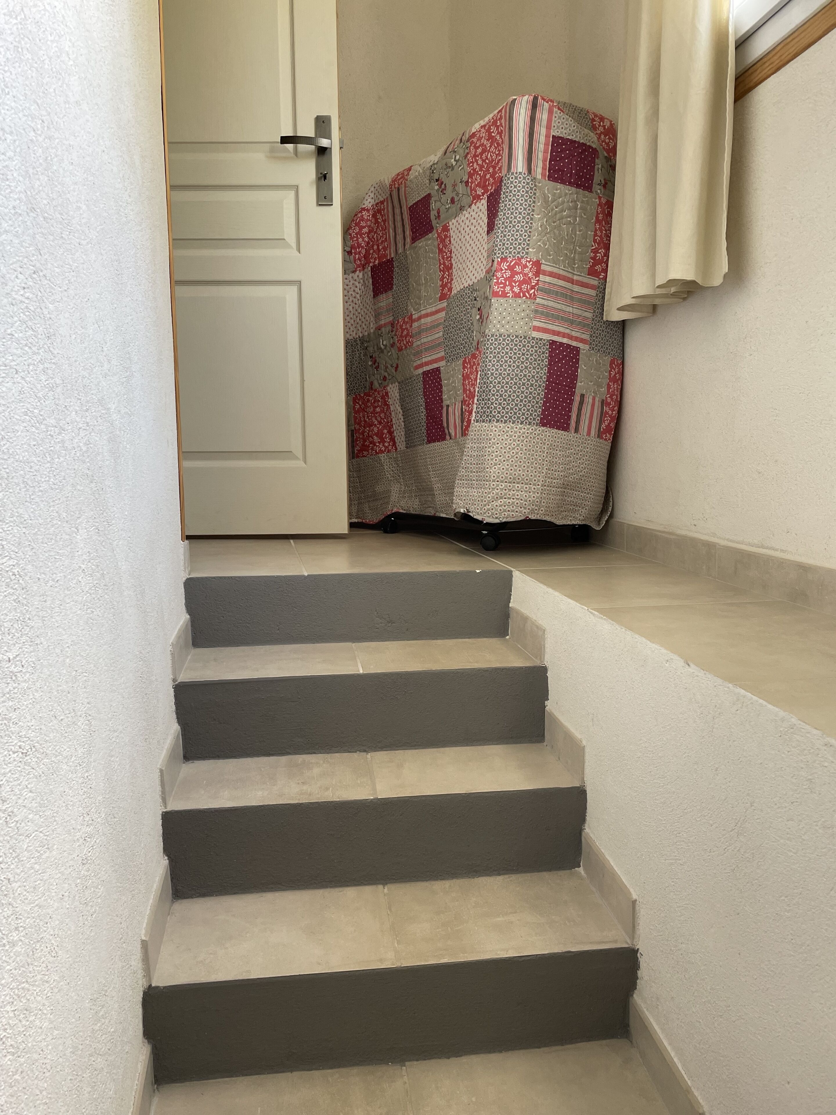 A staircase with a patterned fabric draped over the top landing.
