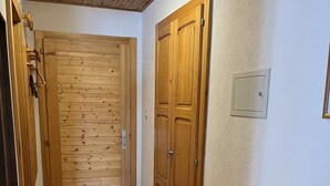 A hallway with wooden doors, a wooden dresser, and a light switch on the wall. - In Evolene, sunny studio with stunning view over the mountains (Evolène)