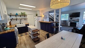 Une cuisine moderne dotée d’un îlot central, d’un plancher en bois et d’un coin repas avec une table blanche.