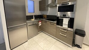 Een moderne keuken met roestvrijstalen apparatuur, een inbouwoven en een raam boven de spoelbak.