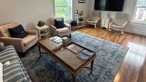A spacious living room with a large window, a flat-screen TV, and a comfortable seating area. - Lakeside three bedroom boathouse. (Wasilla)