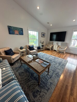 A spacious living room with a large window, a flat-screen TV, and a comfortable seating area. - Lakeside three bedroom boathouse. (Wasilla)