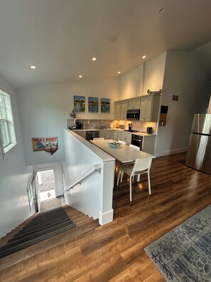 A modern kitchen with wooden flooring, a central island, and a dining area.