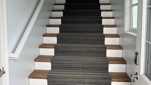 A staircase with alternating white and dark wooden steps leading to a landing. - Lakeside three bedroom boathouse. (Wasilla)