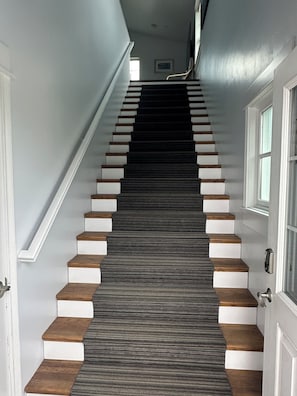 A staircase with alternating white and dark wooden steps leading to a landing. - Lakeside three bedroom boathouse. (Wasilla)