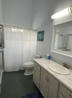Un baño con inodoro, lavamanos y cortina de ducha.