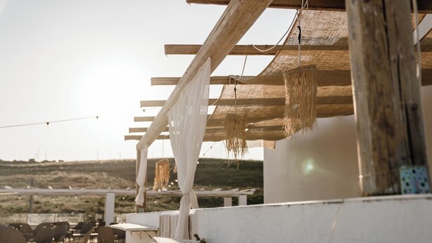 An outdoor seating area with white tables and chairs, a pergola structure, and a view of a distant landscape. - DE MARE WINE RESORT (Ciro Marina)