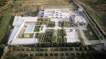 Ein Luftbild eines großen, modernen Gebäudes mit Schwimmbad, mehreren Terrassen und angelegten Gärten.