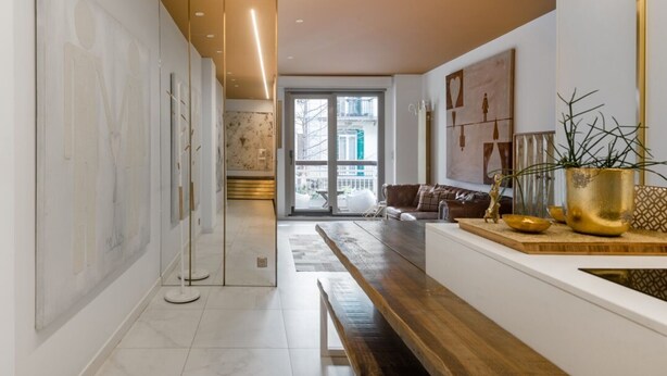 A modern kitchen with a long counter, a bench, and a view of the city through large windows. - Apartment Boulevard luxury by Sebastiana Group (San Sebastián)